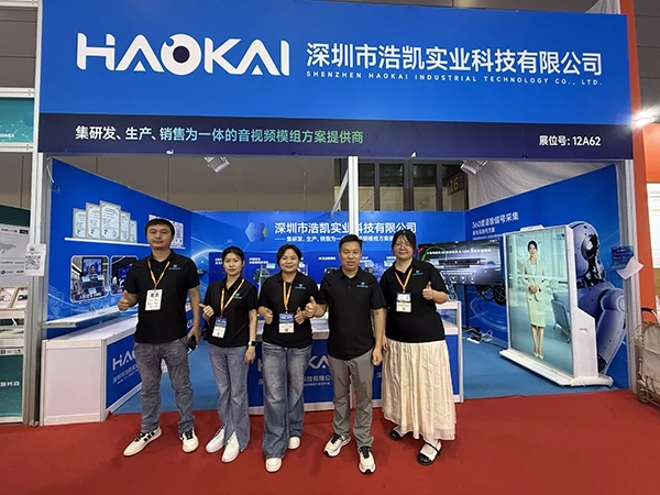 Five HAOKAI team members posing in front of the company exhibition booth at IOTE