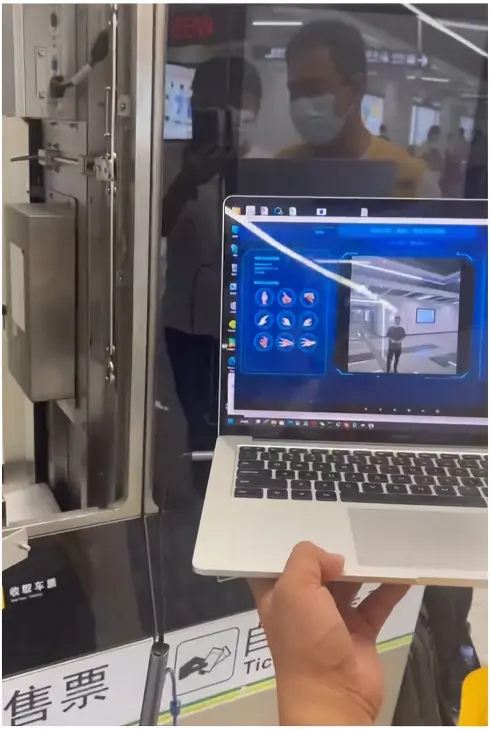 Laptop showing a camera test beside a Shenzhen Metro ticketing terminal